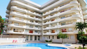 A multi-story building with balconies, a swimming pool, and a small garden area. - Rentalmar Arquus (Salou)