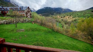 A mountainous landscape with a building featuring multiple balconies and a stone facade. - Apartaments Pleta Bona (La Vall de Boi)