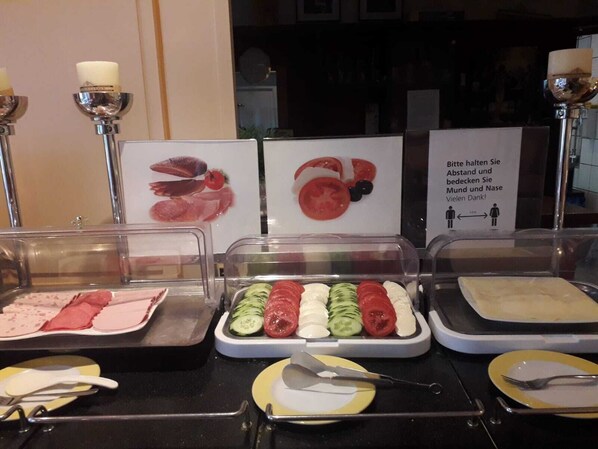 A buffet with various food options including sliced cucumbers, tomatoes, and cheese.