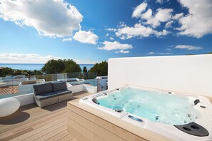 A rooftop deck with a hot tub, outdoor furniture, and a view of the sea. - Insotel Tarida Beach Resort & SPA (Sant Josep de sa Talaia)