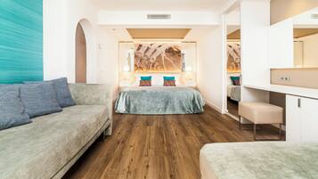 Een moderne hotelkamer met houten vloer, een groot bed met kleurrijke kussens, een bank en een bureau.