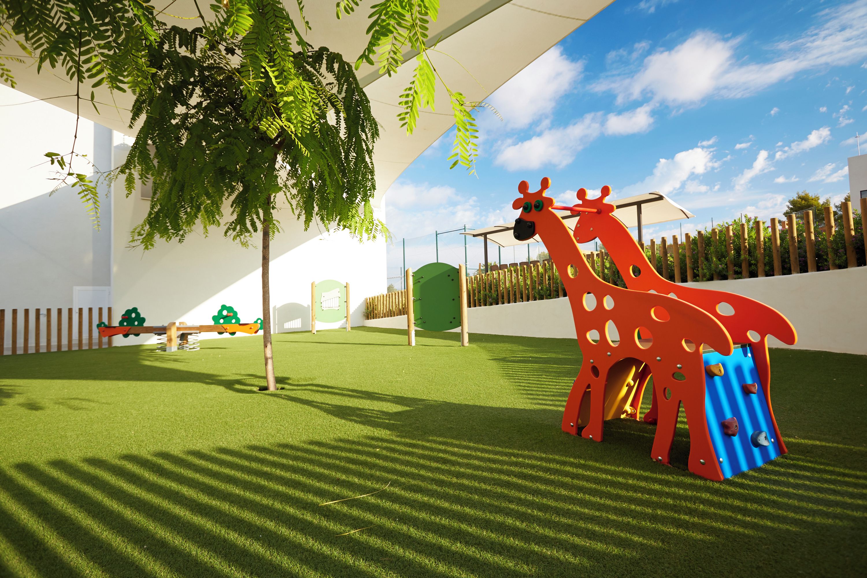 Zona de juegos con un tobogán con forma de jirafa y estructuras para escalar.