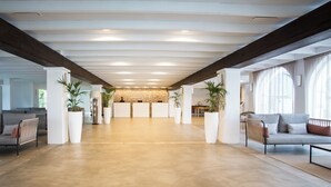 A spacious lobby with a high ceiling, large windows, and a stone wall in the background. - Insotel Tarida Beach Resort & SPA (Sant Josep de sa Talaia)