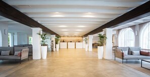 Un hall d’entrée spacieux avec un plafond haut, de grandes fenêtres et un mur en pierre en arrière-plan.