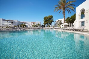 A clear swimming pool with lounge chairs and umbrellas, surrounded by white buildings and palm trees. - Insotel Tarida Beach Resort & SPA (Sant Josep de sa Talaia)