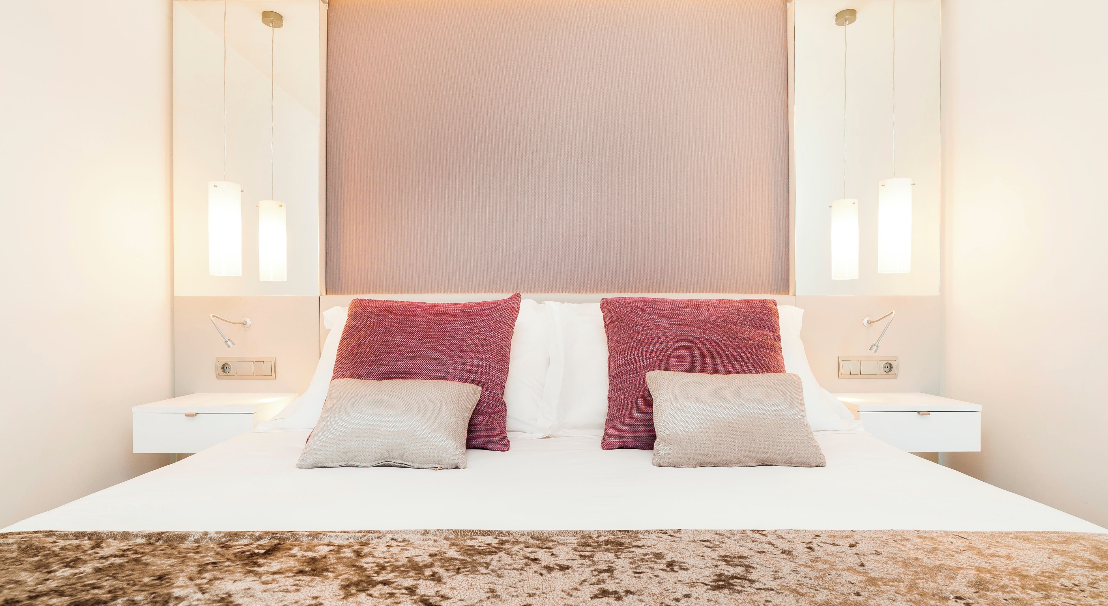 Ein ordentlich eingerichtetes Hotelzimmer mit einem großen Bett, zwei Nachttischen und einem Kopfteil mit einer hellen Abdeckung.