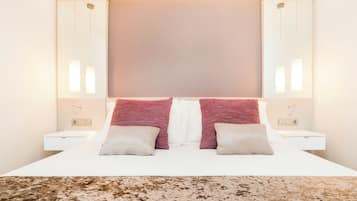Quarto de hotel bem organizado, com uma cama grande, duas mesas de cabeceira e cabeceira com painel claro.