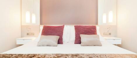 Habitación de hotel impecable con una cama grande, dos mesitas de noche y un cabecero con un panel de color claro.