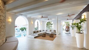 A spacious living area with a large sofa, a coffee table, and a view of the pool. - Insotel Tarida Beach Resort & SPA (Sant Josep de sa Talaia)