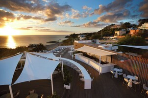 Terraza en la azotea con mobiliario exterior, vista al mar y un atardecer.
