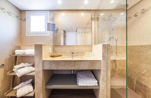 Une salle de bain moderne avec une douche à parois de verre, un meuble-lavabo et un miroir. On y trouve également des étagères avec des serviettes et des articles de toilette.