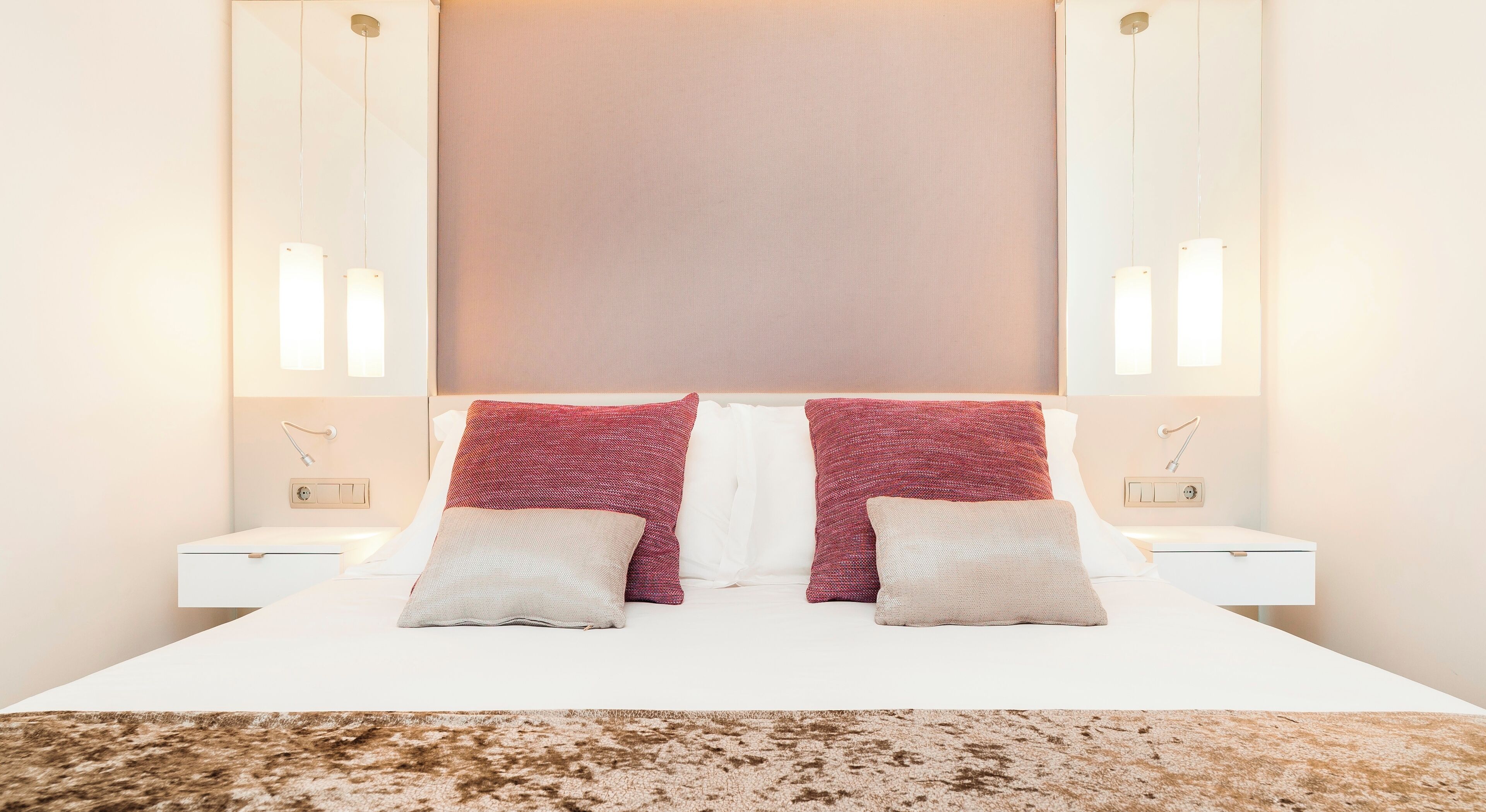 Une chambre d’hôtel avec un grand lit, deux tables de chevet et une tête de lit dotée d’un panneau lumineux.