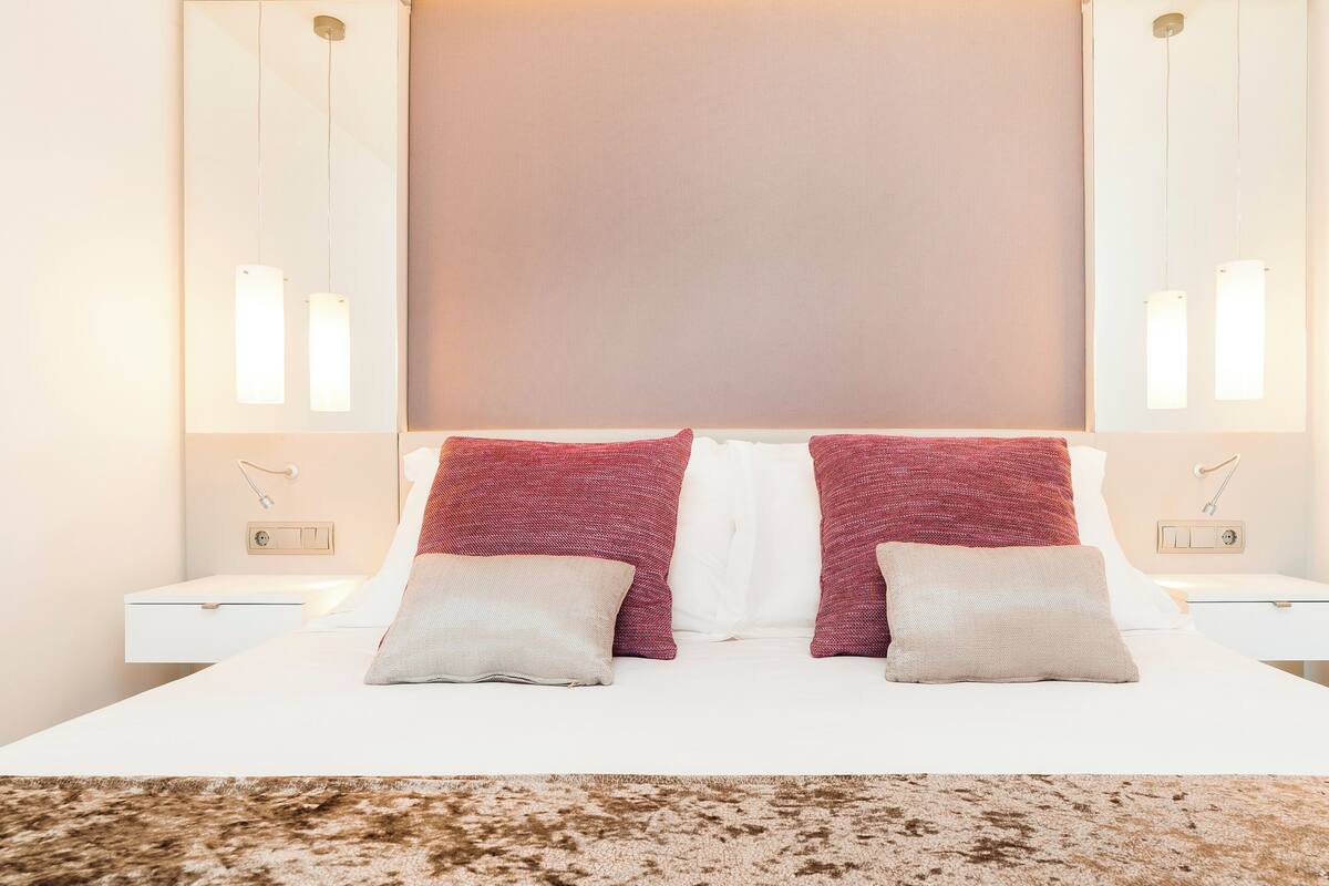 Une chambre d’hôtel avec un grand lit, deux tables de chevet et une tête de lit dotée d’un panneau lumineux.