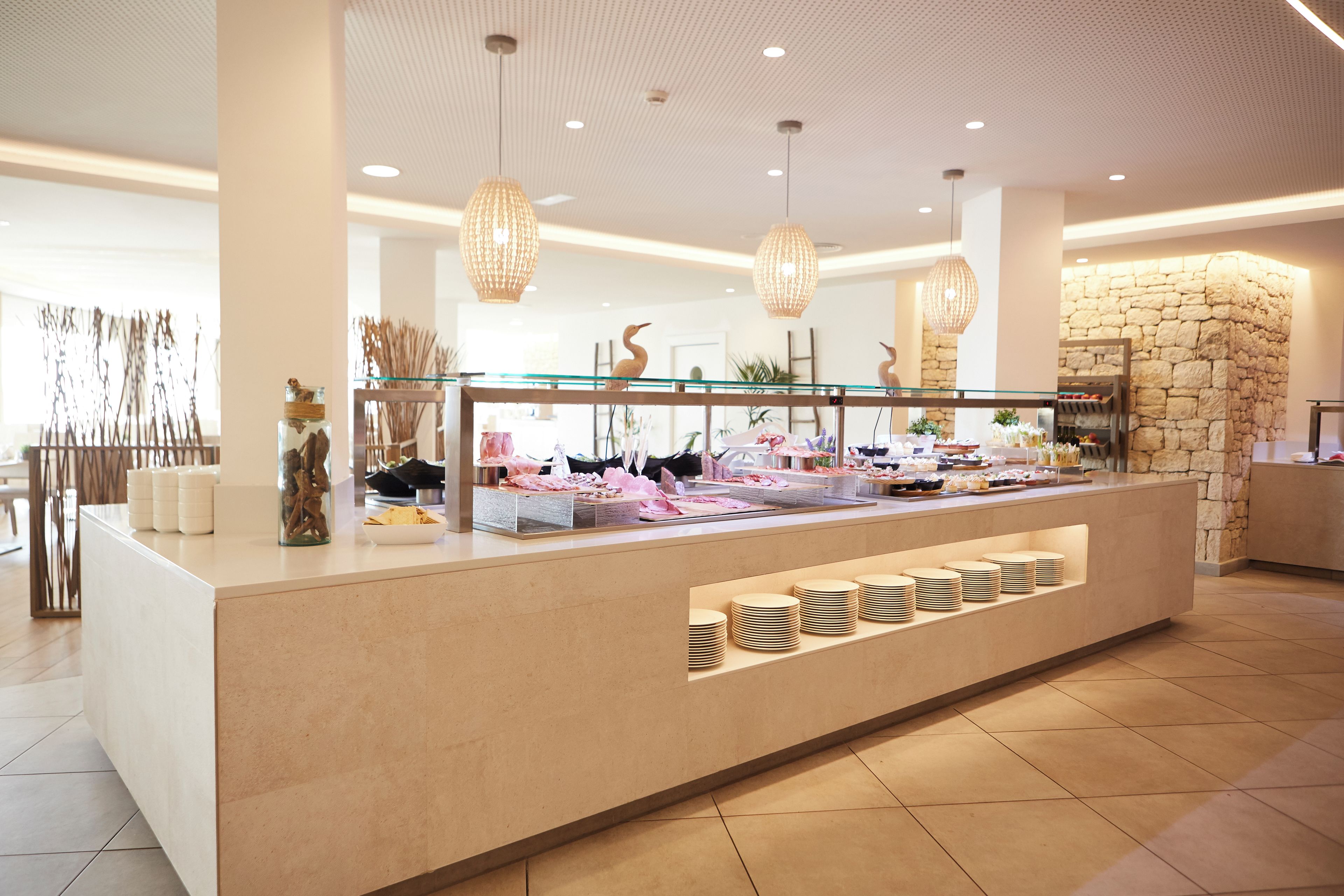 Eine moderne Hotelrezeption mit Glastresen, einer Wand mit Steinakzenten und hängenden Pendelleuchten.