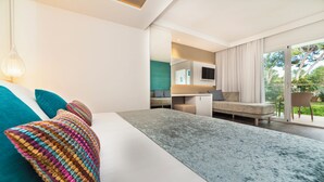A modern bedroom with a large bed, a desk, and a balcony with a view of greenery. - Insotel Tarida Beach Resort & SPA (Sant Josep de sa Talaia)