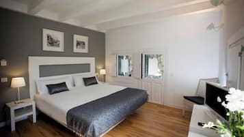 A modern bedroom with a large bed, bedside tables, a desk with a computer, and framed artwork on the wall.