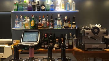 A bar area with a variety of liquor bottles on shelves and a digital payment terminal.