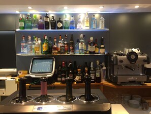 Un espace bar avec une variété de bouteilles d’alcool exposées sur des étagères et un terminal de paiement numérique.