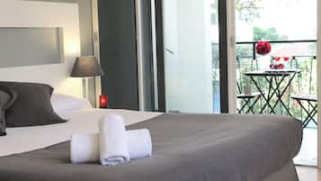 Habitación de hotel con cama, lámpara y balcón con mesa y sillas.