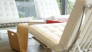 Una habitación moderna con un sofá de cuero blanco, una mesita de madera y una lámpara de pie roja.