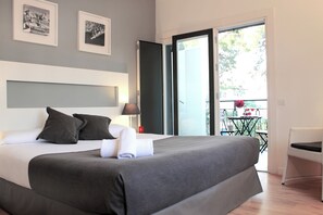 A modern hotel room with a large bed, a balcony with a table and chairs, and framed pictures on the wall. - Sitges (Sitges)