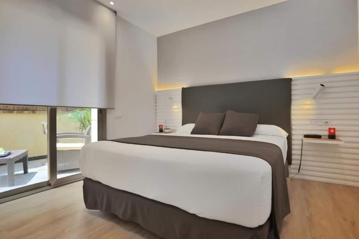 Habitación de hotel moderna con una cama grande, una mesita y vistas al exterior.