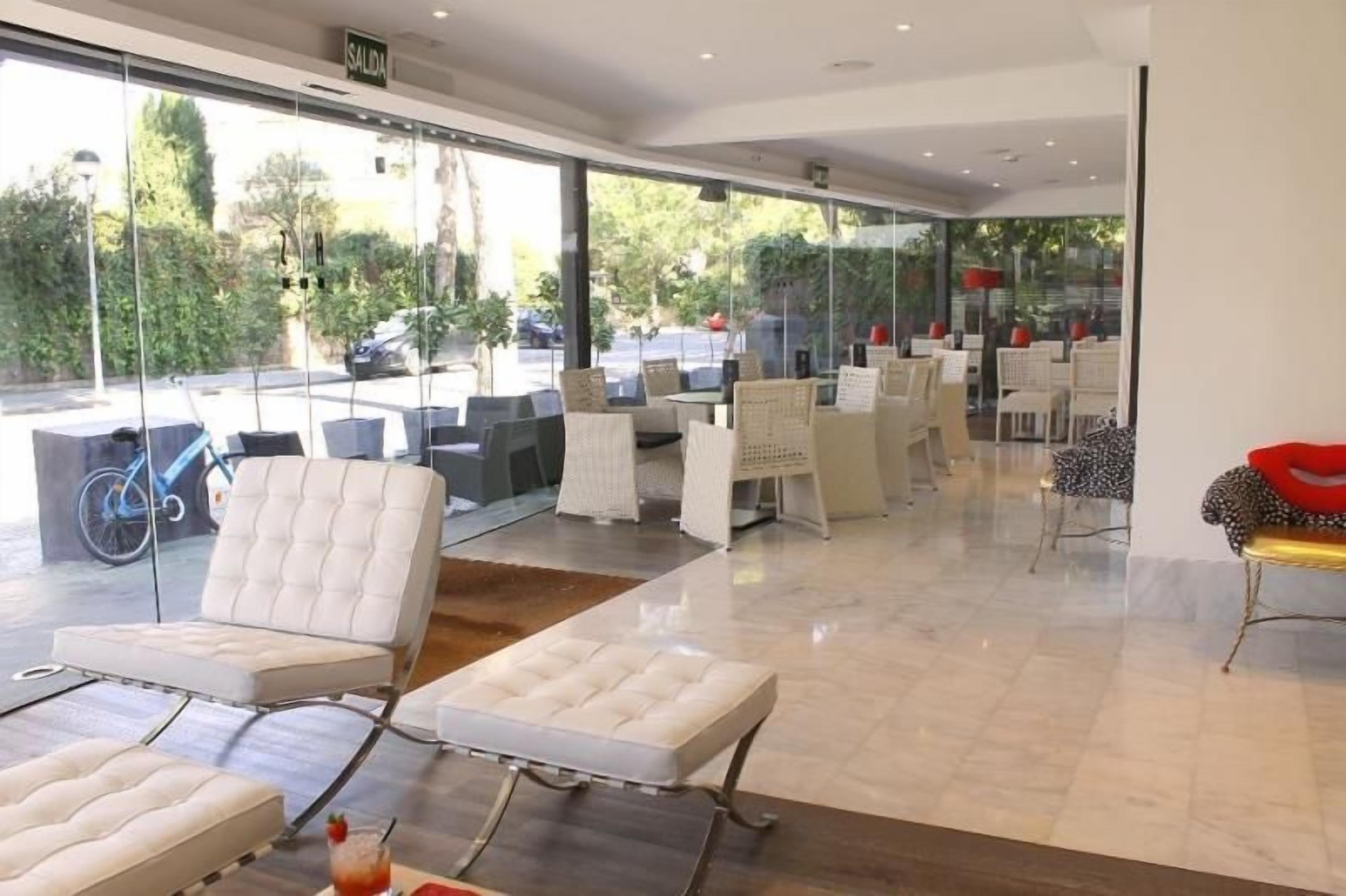 A modern indoor seating area with cushioned chairs and tables, large windows offering a view of the outdoors.