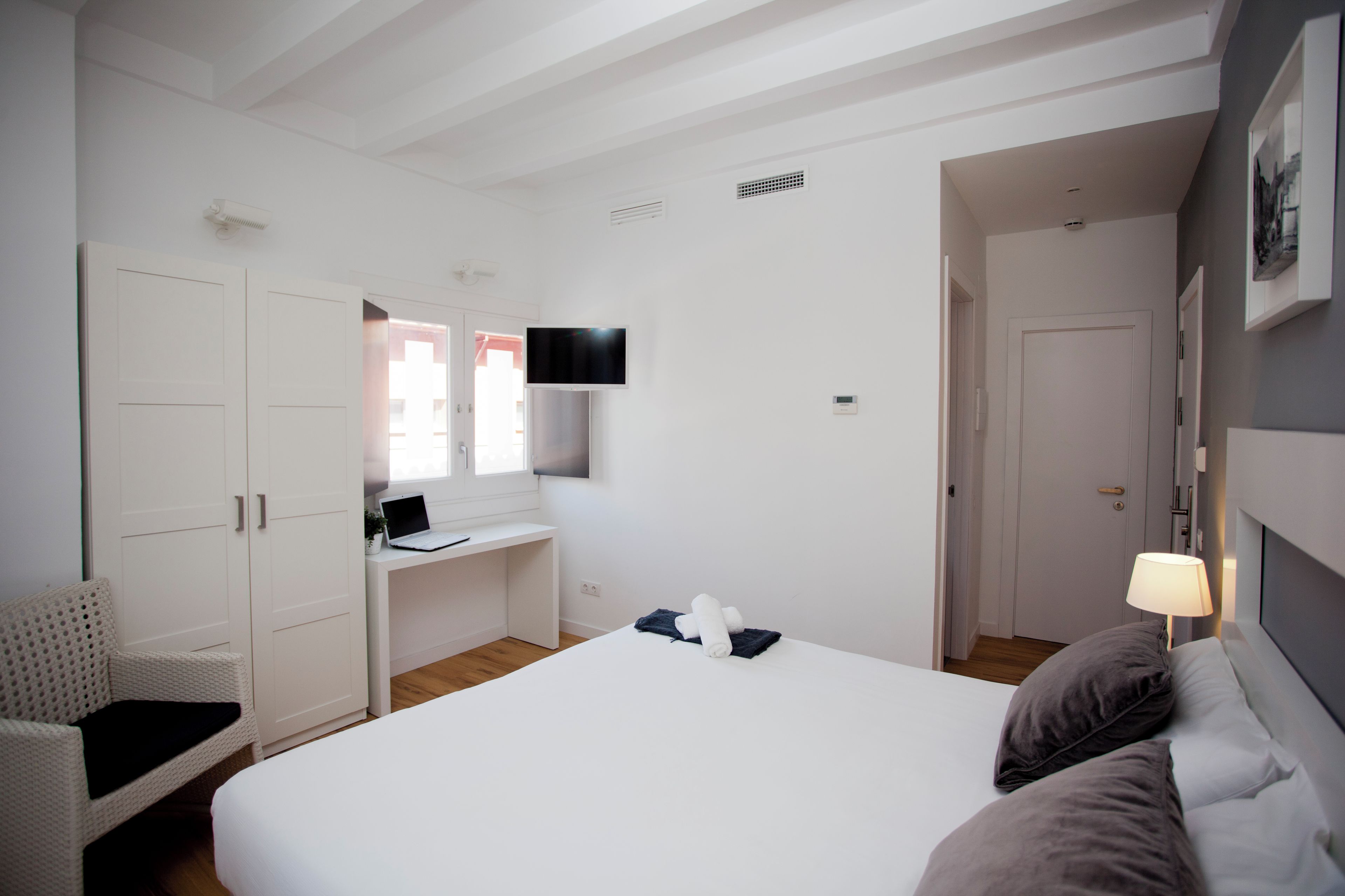 Una habitación de hotel con una cama, un escritorio, una silla, un televisor y una puerta.