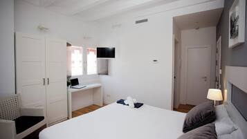 Una habitación de hotel con una cama, un escritorio, una silla, un televisor y una puerta.