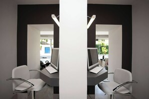 A mirrored view of a modern interior with two white chairs, a desk with a laptop, and a large window. - Sitges (Sitges)