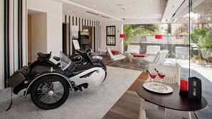 A modern hotel lobby with a classic motorcycle, seating area, and a view of the outdoors. - Sitges (Sitges)