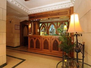 A reception area with a wooden counter, a stained glass window, and a lamp. - Santo Domingo De Silos (Santo Domingo de Silos)