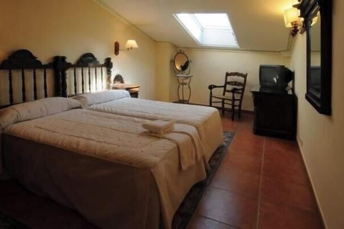 A bedroom with a bed, a chair, a television, and a mirror.