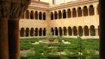 Un patio con una fuente, rodeado de arcos y columnas, que sugiere un lugar histórico o cultural.