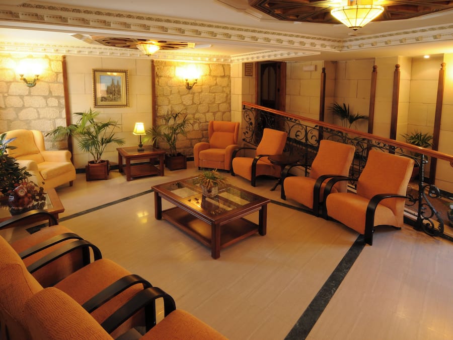A lobby with a stone wall, a staircase, and orange seating.