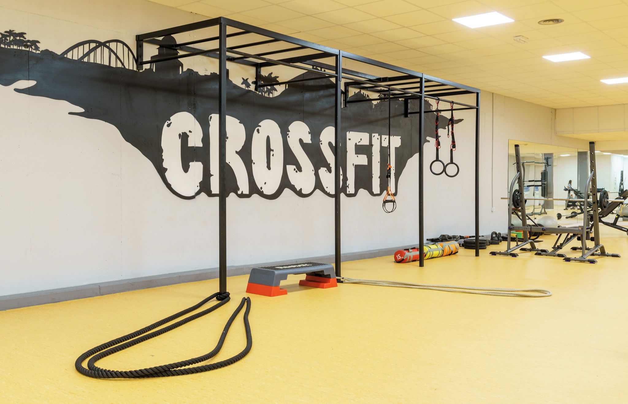 Un gimnasio con un gran mural que dice "CROSSFIT" y diverso equipo de ejercicio.