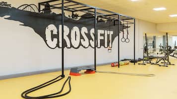Un gimnasio con un gran mural que dice "CROSSFIT" y diverso equipo de ejercicio.