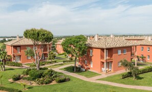 A residential area with terracotta-roofed buildings, well-maintained lawns, and trees. - Ilunion Sancti Petri (Chiclana de la Frontera)