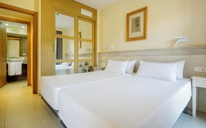 A hotel room with a large bed, a bathroom with a mirror and sink, and a framed picture on the wall. - Ilunion Sancti Petri (Chiclana de la Frontera)