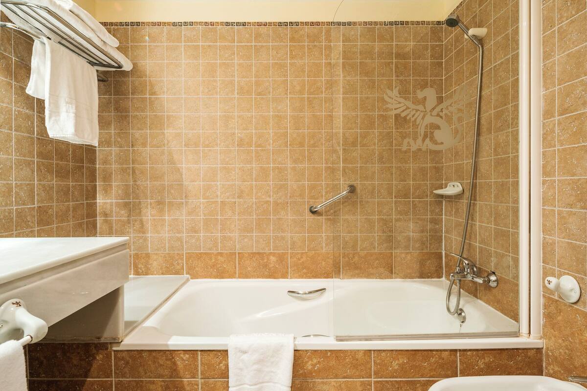 A bathroom with a bathtub, a shower, and a sink.