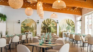 Un espace repas avec des tables rondes, des chaises et des luminaires suspendus en forme de suspensions tissées.