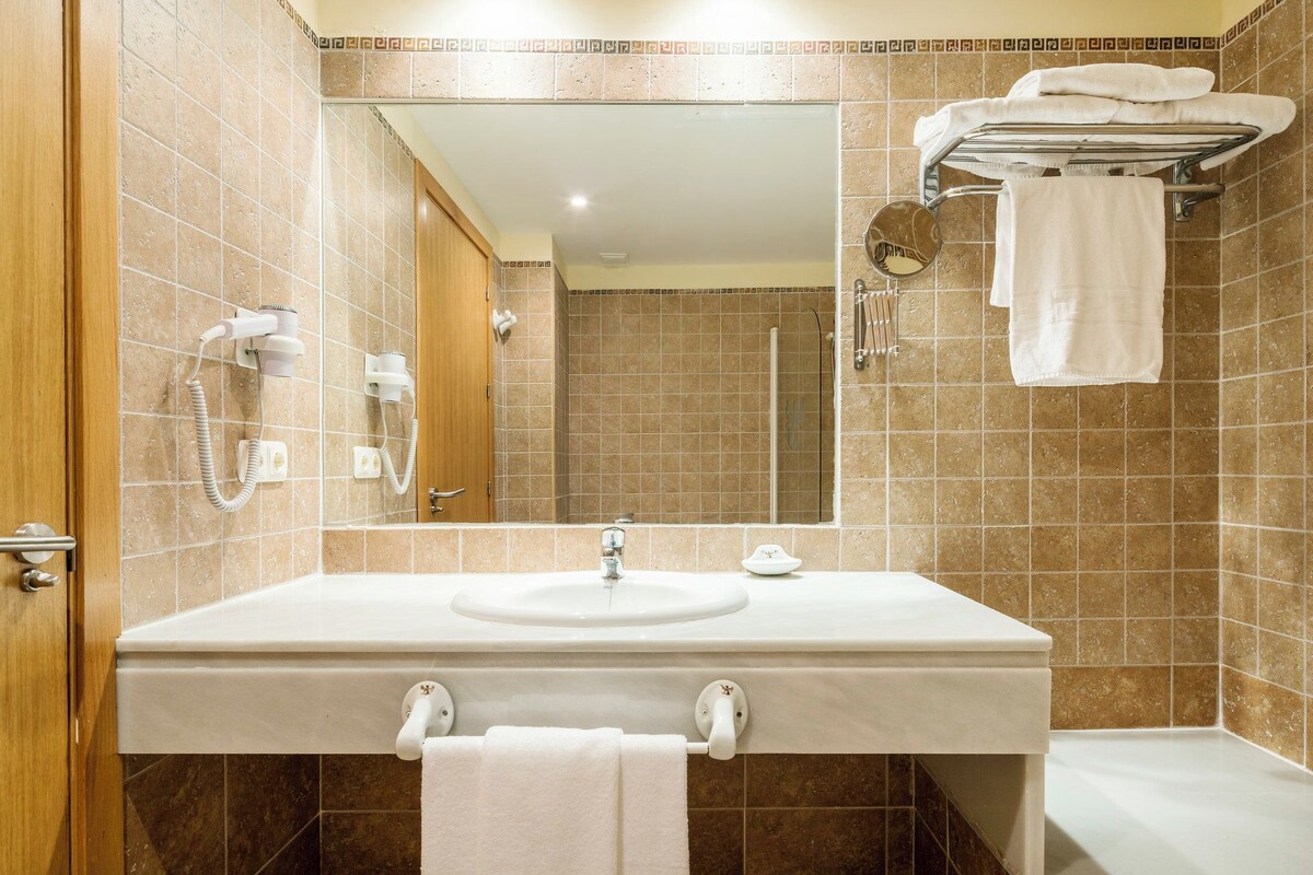 A bathroom with a sink, mirror, and towel rack.