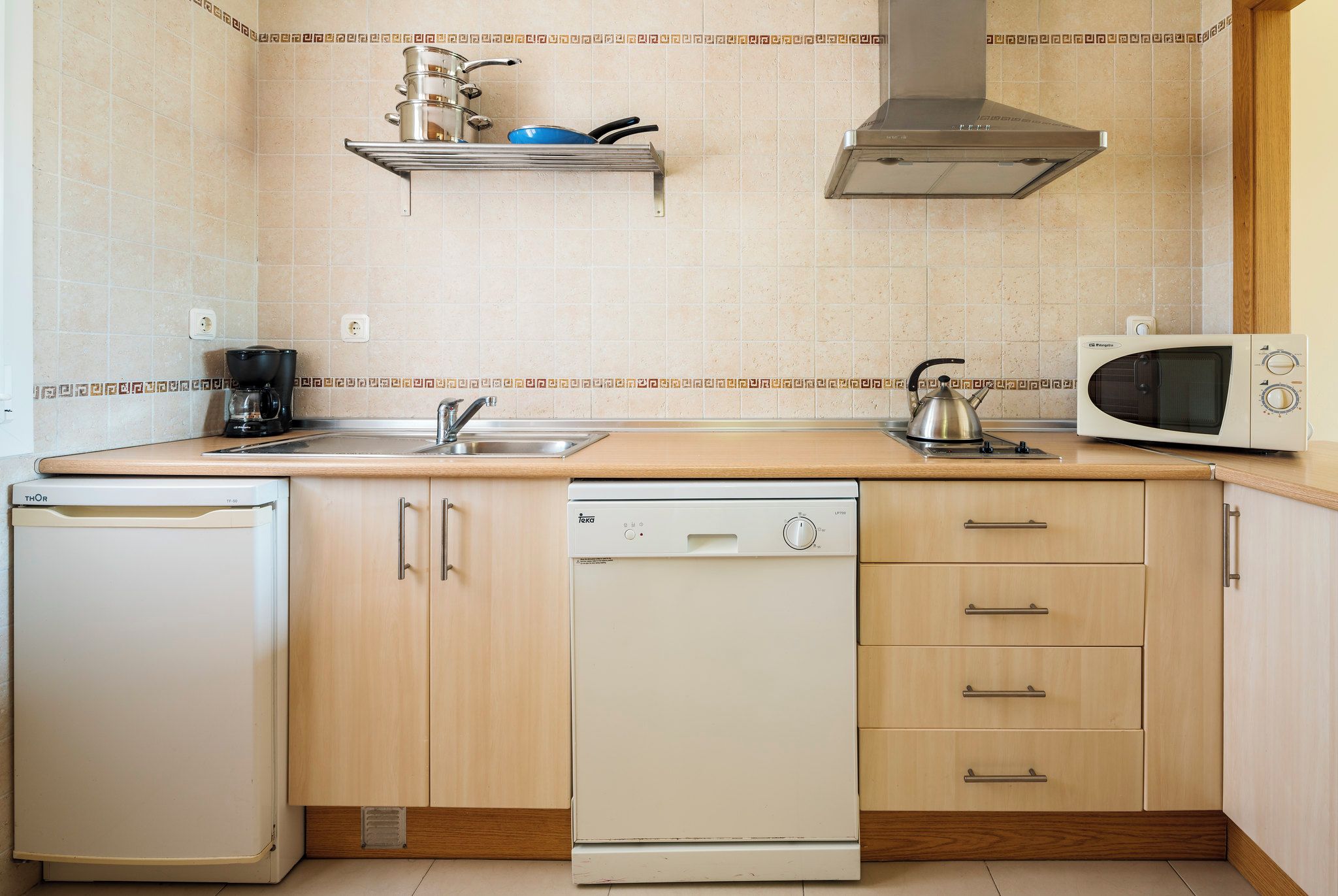 Cocina compacta equipada con lavavajillas, microondas, hervidor de agua y cafetera.