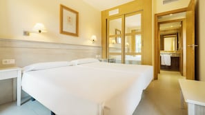 A hotel room with two beds, a bathroom with a mirror, and a small table. - Ilunion Sancti Petri (Chiclana de la Frontera)