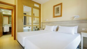 Une chambre d’hôtel avec un grand lit, une salle de bain avec un miroir et un lavabo, et un tableau encadré au mur.