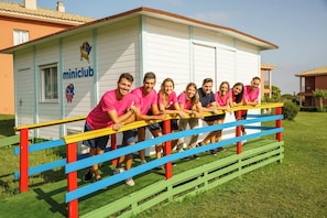 A group of people leaning on a colorful playground structure in front of a building labeled "miniclub". - Ilunion Sancti Petri (Chiclana de la Frontera)