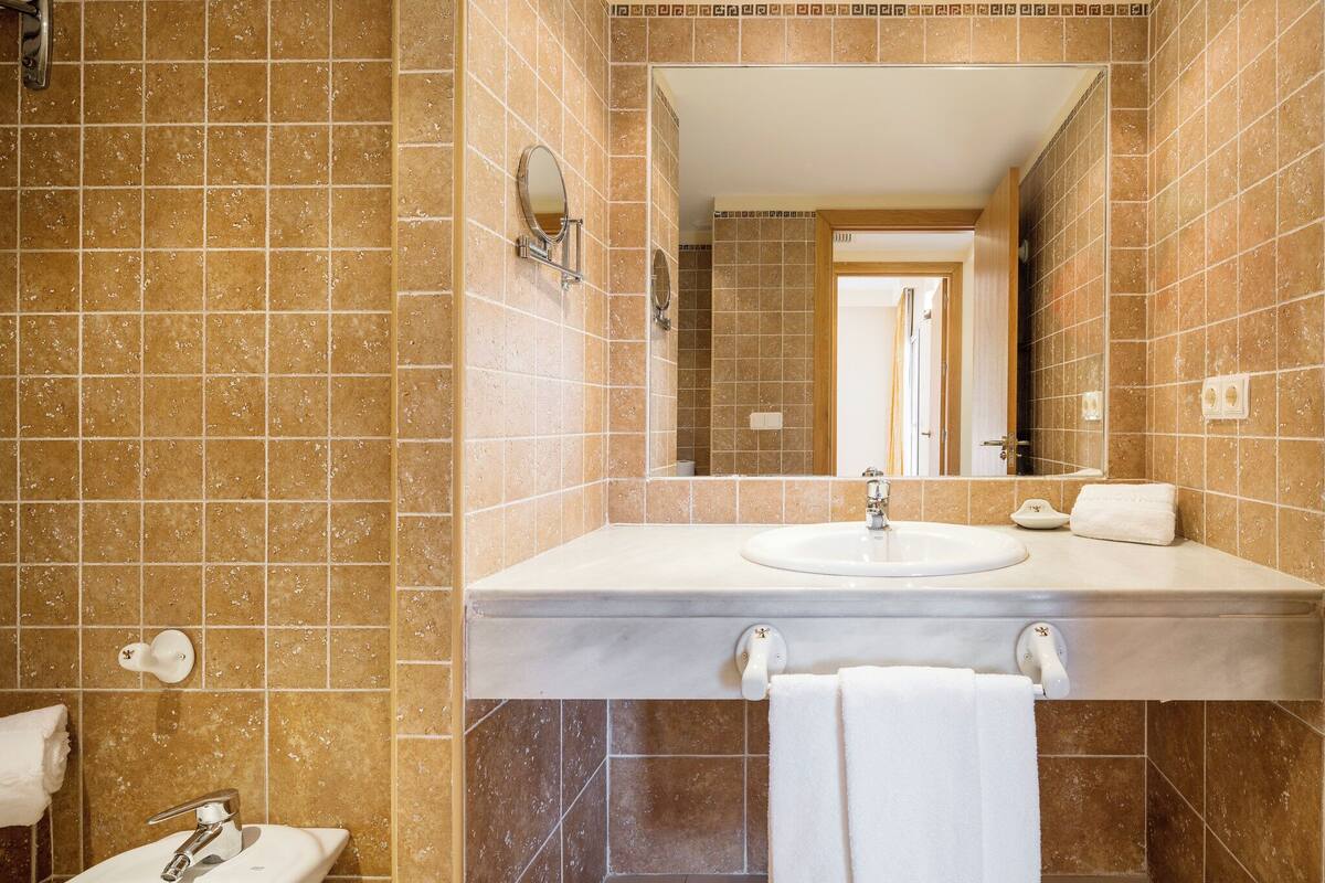 A bathroom with a sink, mirror, and two towel racks.