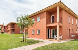 A multi-story residential building with a flat roof, balconies, and a small patio area with outdoor furniture. - Ilunion Sancti Petri (Chiclana de la Frontera)