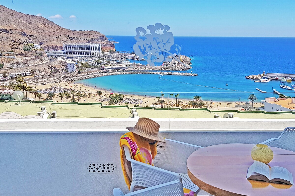 Vista costeira com praia, barcos e um conjunto de edifícios.