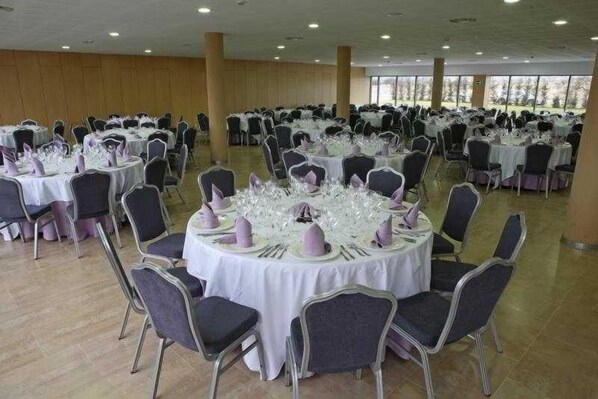 A banquet hall with round tables set for events, featuring white tablecloths and purple napkins. - Alda El Espinar (El Espinar)